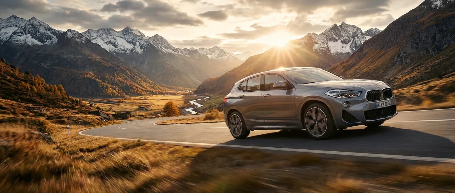 BMW X2 sDrive 18d DCT roulant sur une route de montagne au coucher du soleil